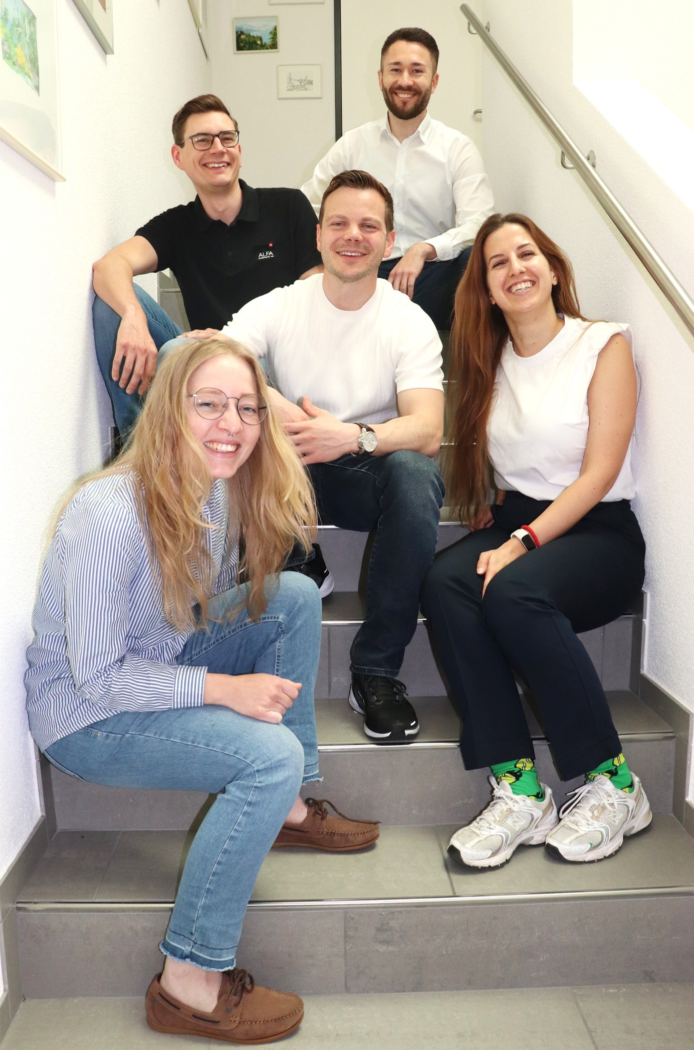 Karriere 15 ALFA-Team sitzt gemeinsam auf einer Treppe im Bürogebäude